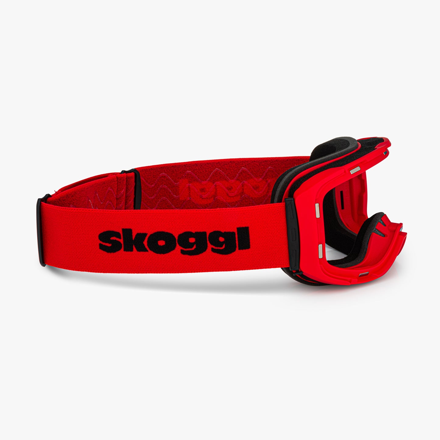 Red ski and snowboard goggle frames with black interior padding and an adjustable red strap featuring the brand name 'Skoggl' in black letters. Shown without lenses to highlight the magnetic lens slot, set against a plain white background. Perfect for customizable, high-performance ski and snowboard gear.