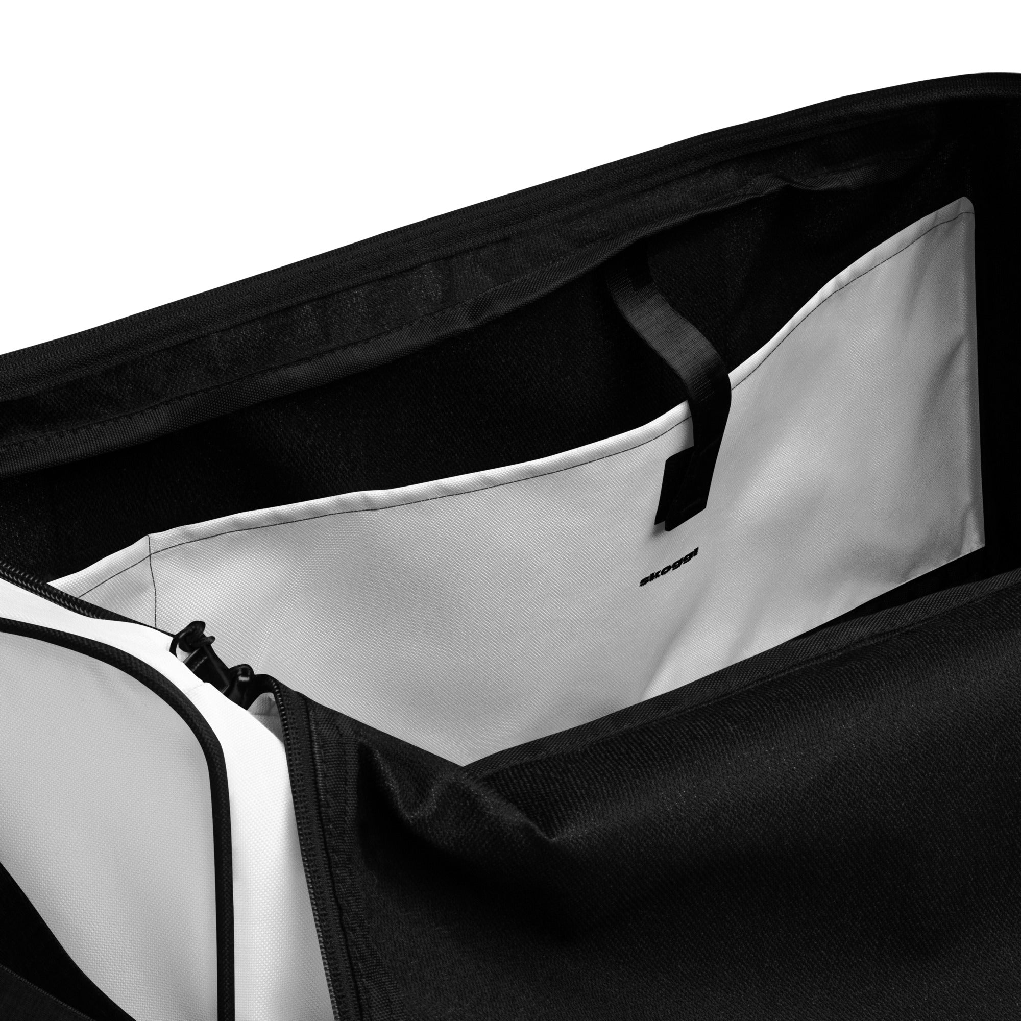 Close-up of a side inside pocket in a black and white gym bag with a visible skoggl brand logo.