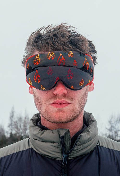 Close-up of a model wearing Flare Vision ski and snowboard goggles, showcasing a sleek design with red fire graphics on the lens. The goggles feature a secure fit, modern frame, and high-performance lenses, combining bold style and optimal clarity for the slopes.
