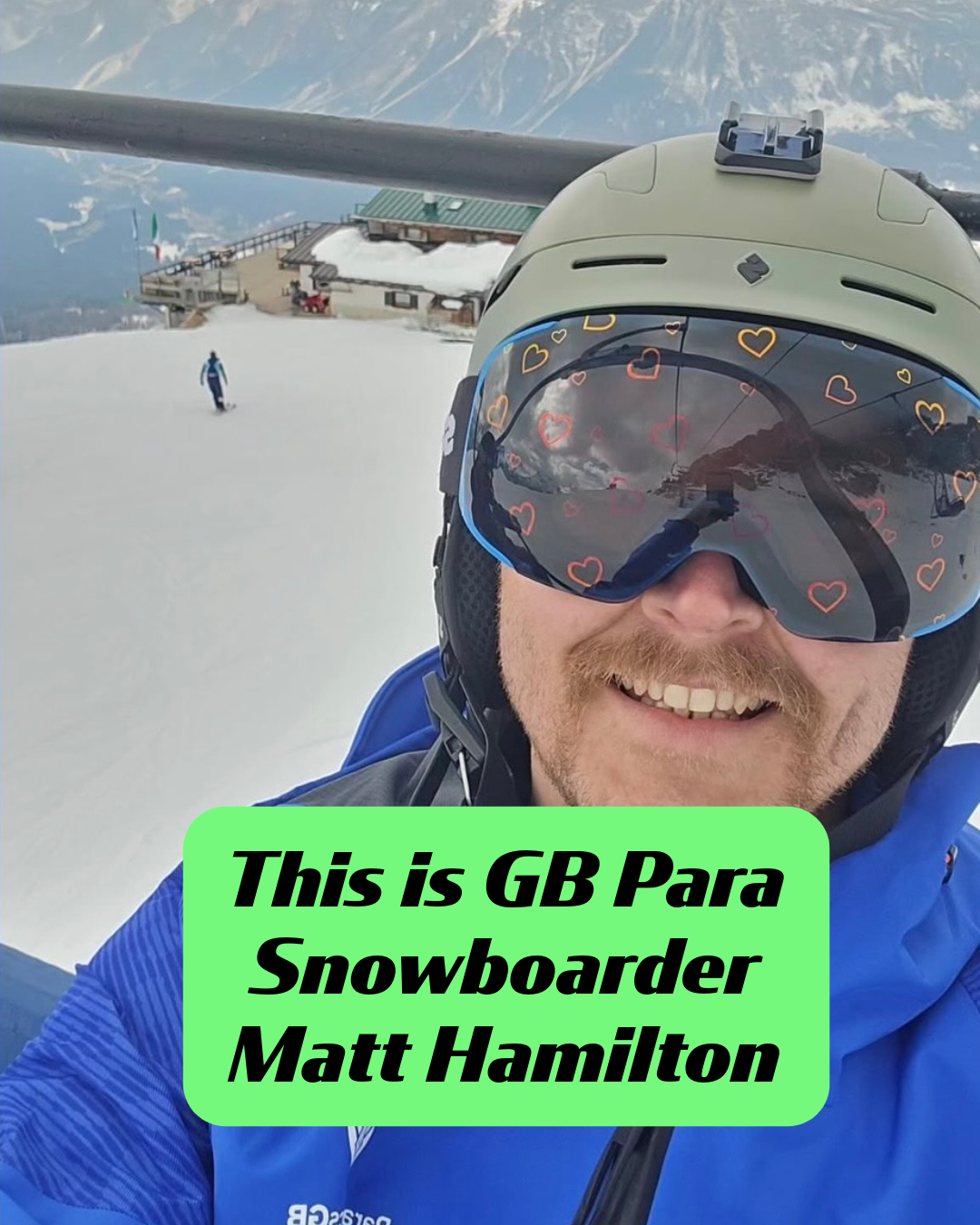 A selfie of GB Para Snowboarder Matt Hamilton on a ski lift in the Italian mountains. He is smiling and wearing custom Skoggl reflective ski and snowboard goggles goggles with orange and red heart outlines. A green text box identifies him as "GB Para Snowboarder Matt Hamilton.