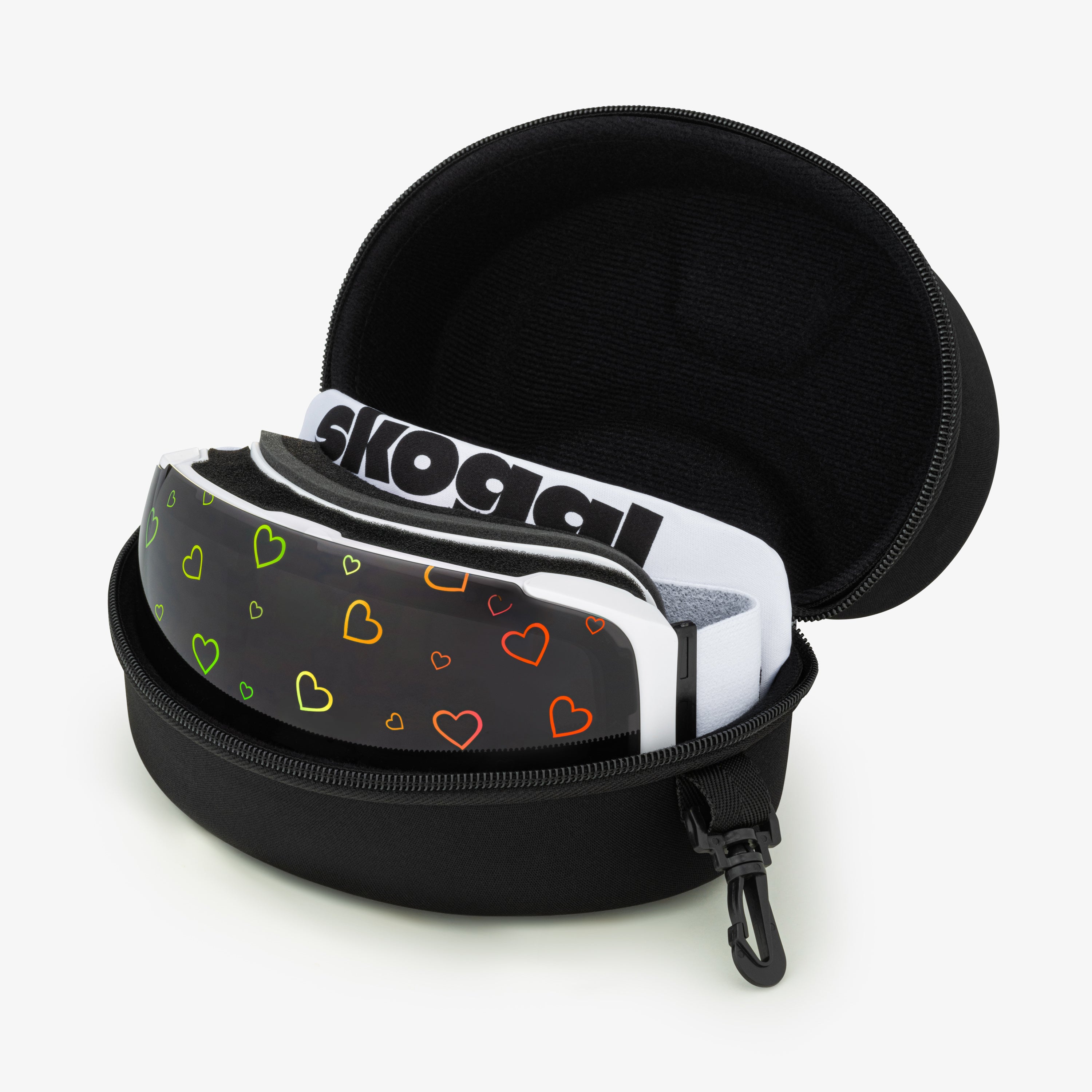 A black ski and snowboard goggle case with a zipper and a small attachment hook, holding a pair of ski goggles inside. The goggles are wrapped in a white dustbag with 'Skoggl' printed on it. The front of the goggles features a colorful heart pattern on a black background, combining style and functionality for winter sports.