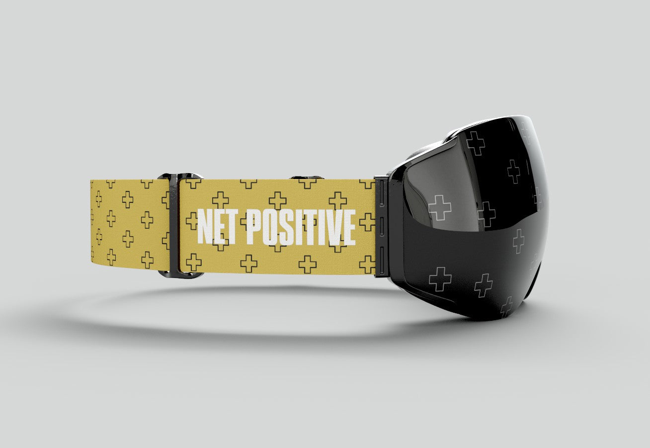 Close-up of the custom interchangeable ski and snowboard goggle strap for John Crist’s Net Positive team, featuring a yellow woven design with black patterns, white logo, and durable black adjustment clips for a custom fit.