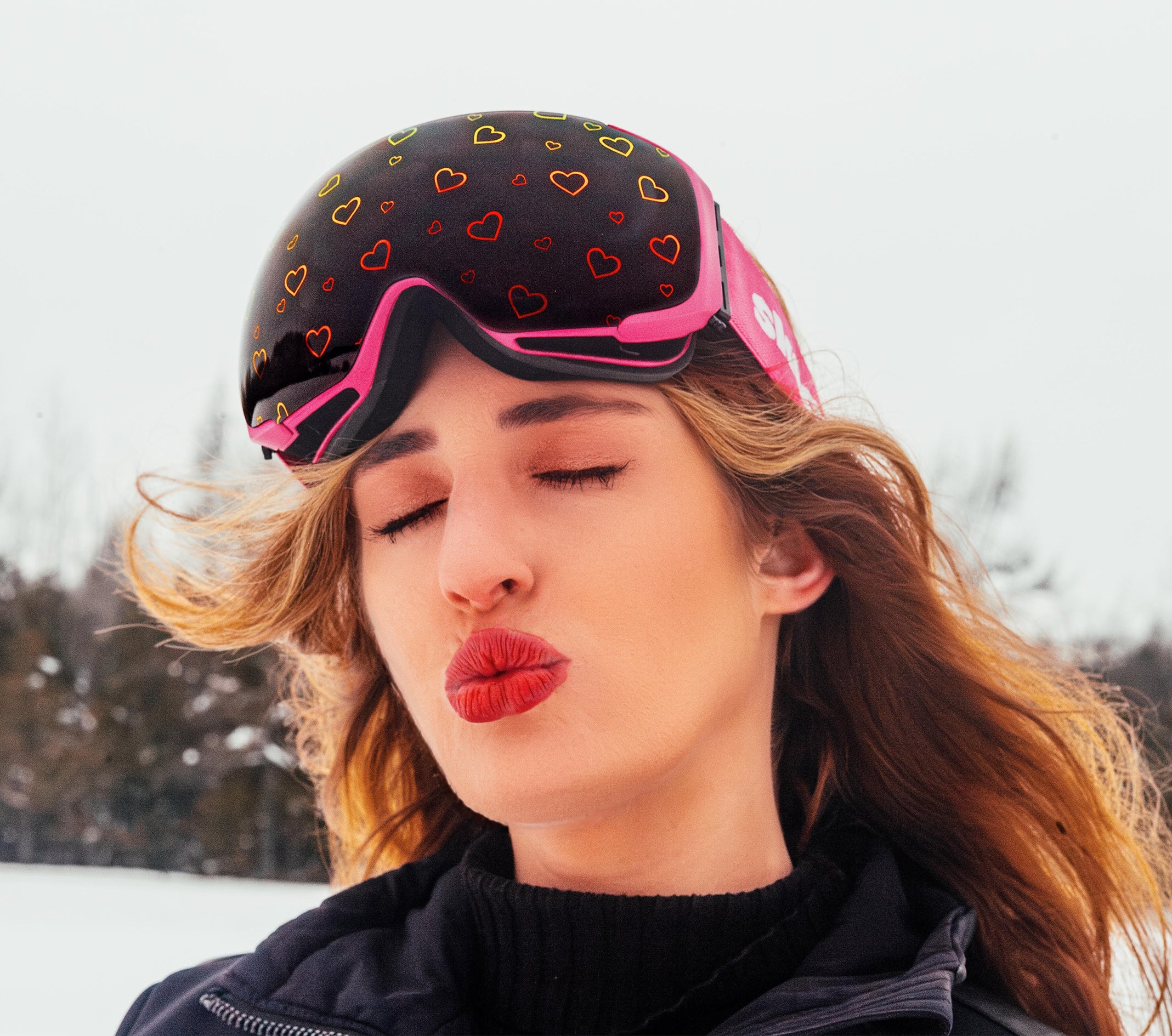 Close-up of a model wearing Frost Love goggles, showcasing a sleek design with playful heart graphics on the lenses. The goggles feature a secure fit, modern frame, and high-performance lenses, combining charming style and optimal clarity for the slopes.