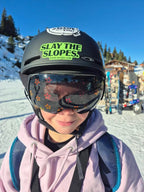 GB Freestyle Skiing Champion Hatti Wilson wearing Skoggl children's ski goggles with orange star-patterned magnetic lenses and a black 'Slay the Slopes' sticker from Skoggl on her helmet.