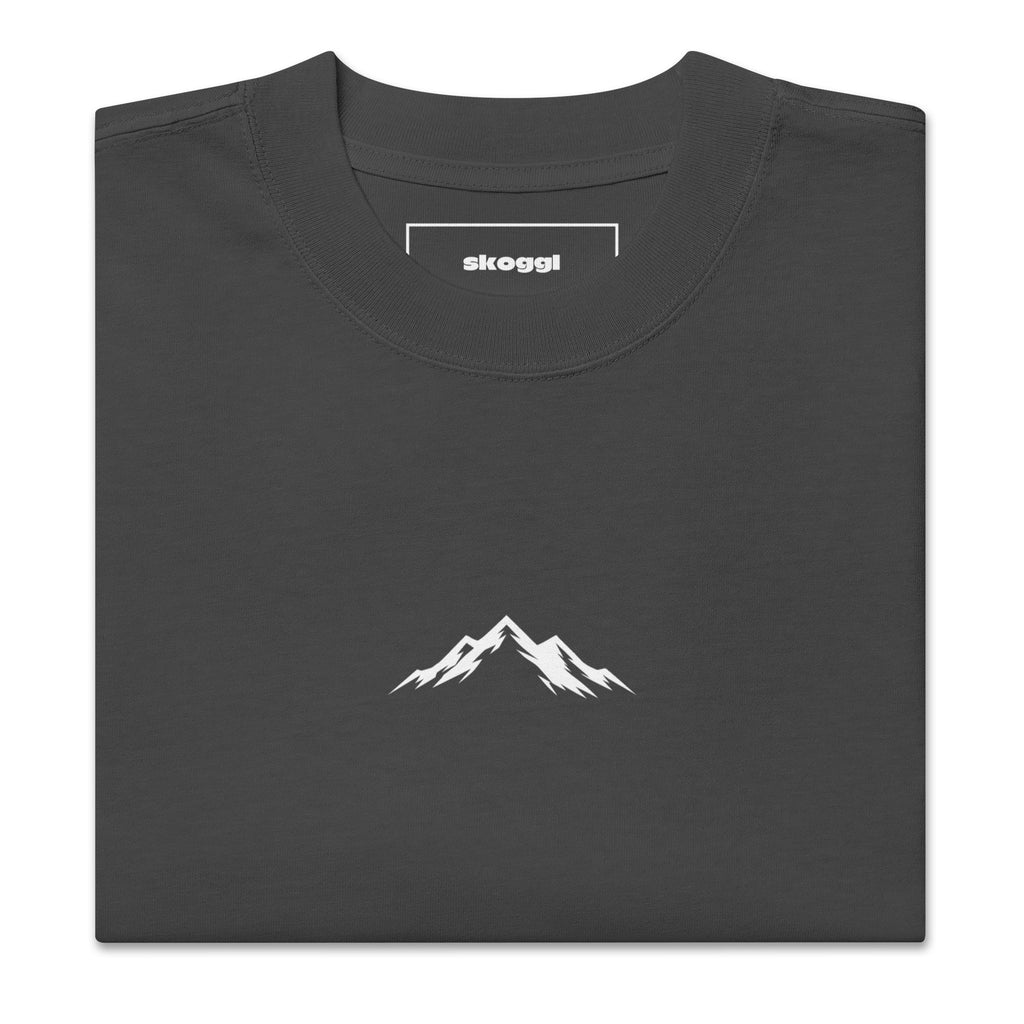 Close-up detail of the white Skoggl mountain logo printed on heavyweight 100% premium carded cotton in Faded Black.