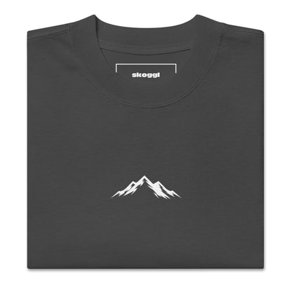 Close-up detail of the white Skoggl mountain logo printed on heavyweight 100% premium carded cotton in Faded Black.
