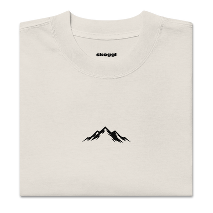 Beige t-shirt with black mountain design and 'skoggl' branding on a white background