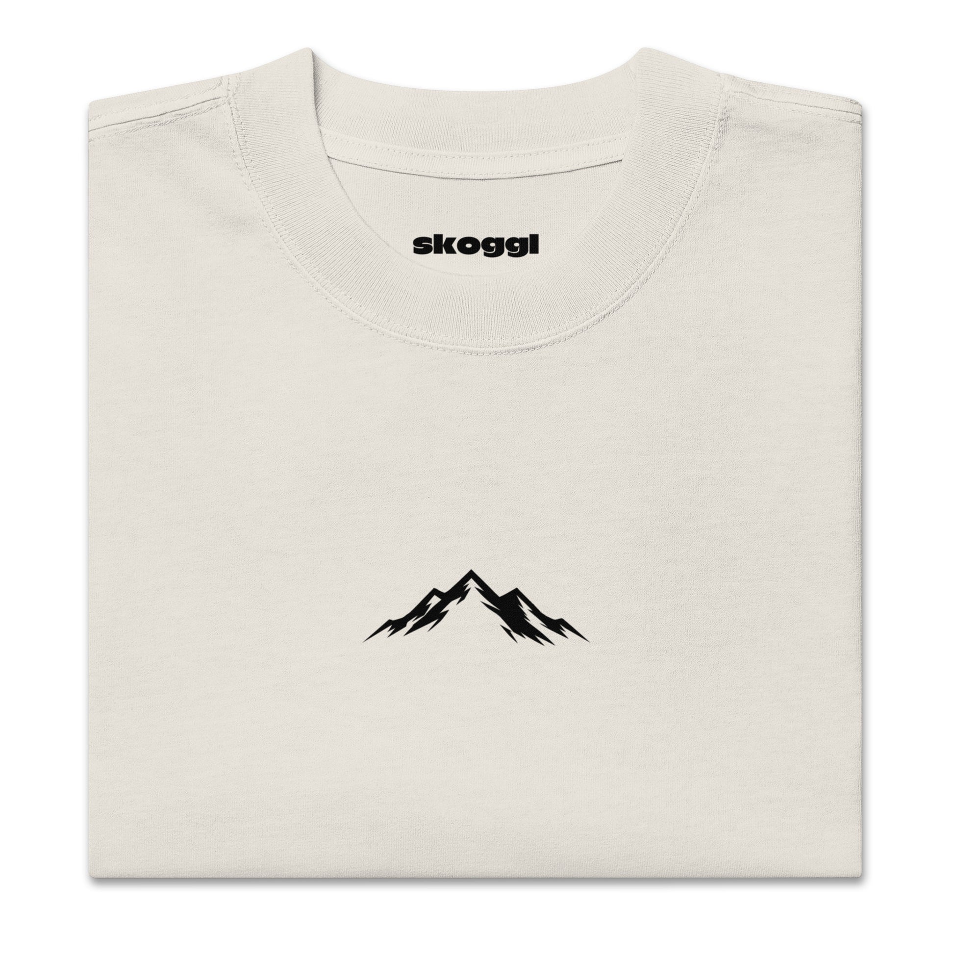 Close-up detail of the black Skoggl mountain logo printed on heavyweight 100% premium carded cotton in Washed Oat.