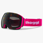 Diagonal view of Skoggl Lovefrost ski and snowboard goggles with hearts on the lens, featuring a pink frame, pink strap, and magnetic lens system for easy swaps. The playful heart design combines style and performance, making these goggles perfect for skiing, snowboarding, and winter sports.
