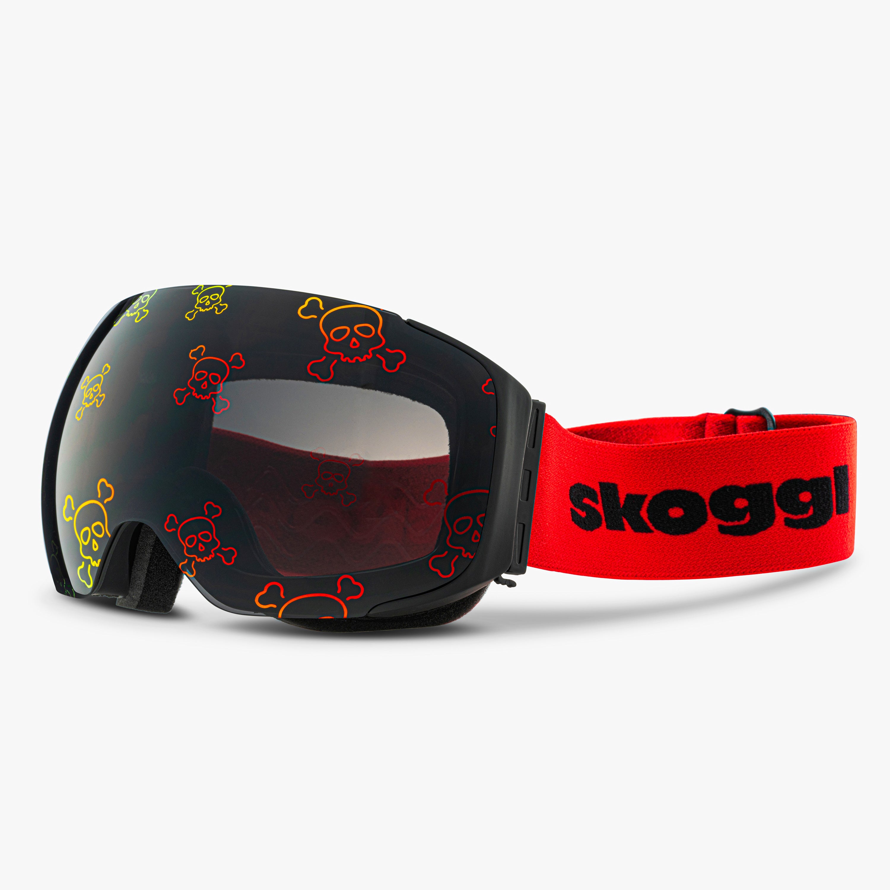 Diagonal view of Skoggl Skull Rider ski and snowboard goggles, showcasing bold skull designs on the lens, a black frame, red strap, and a magnetic lens system for easy swaps. The edgy skull pattern combines style and performance, making these goggles perfect for skiing, snowboarding, and winter sports
