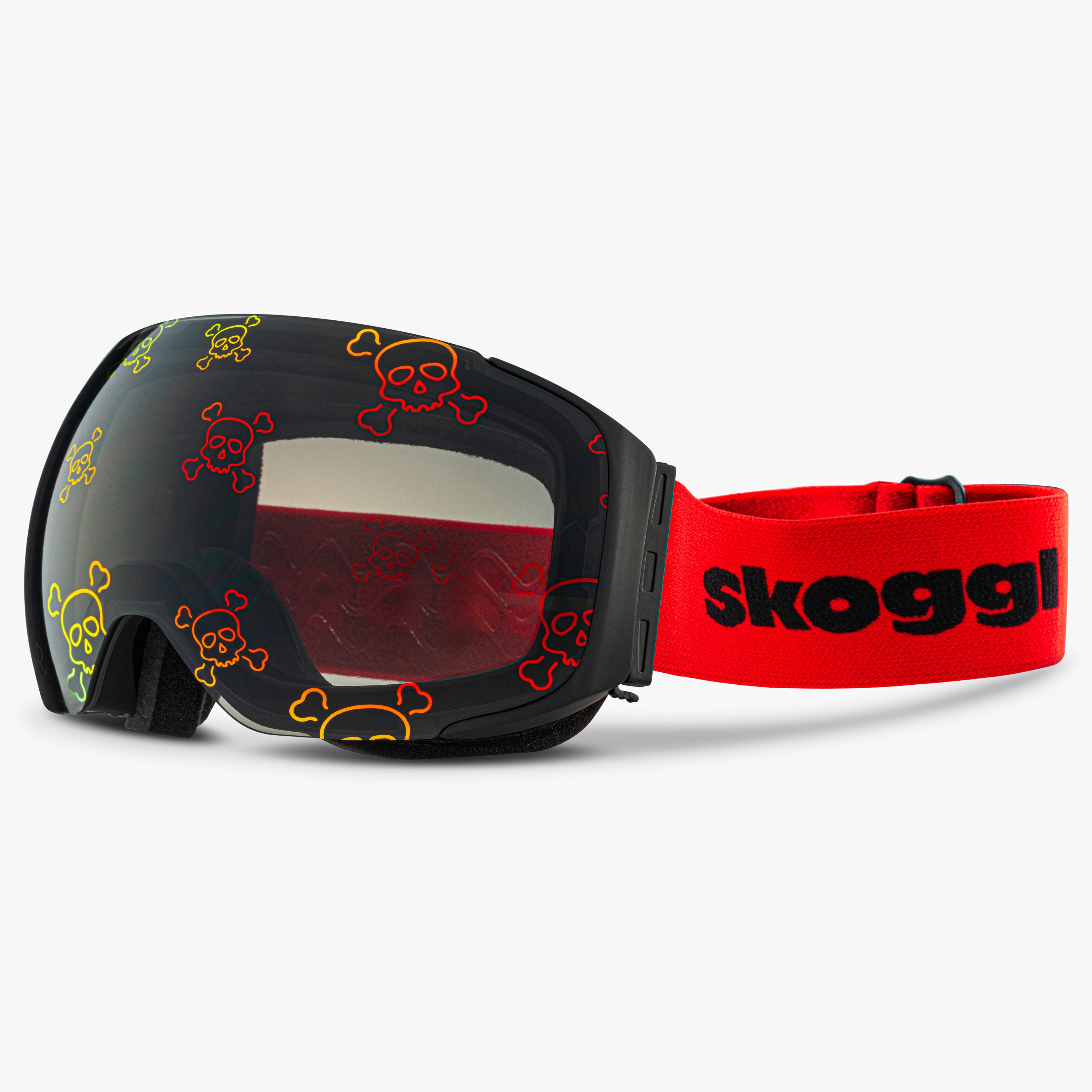 Diagonal view of Skoggl Skull Rider ski and snowboard goggles, showcasing bold skull designs on the lens, a black frame, red strap, and a magnetic lens system for easy swaps. The edgy skull pattern combines style and performance, making these goggles perfect for skiing, snowboarding, and winter sports.