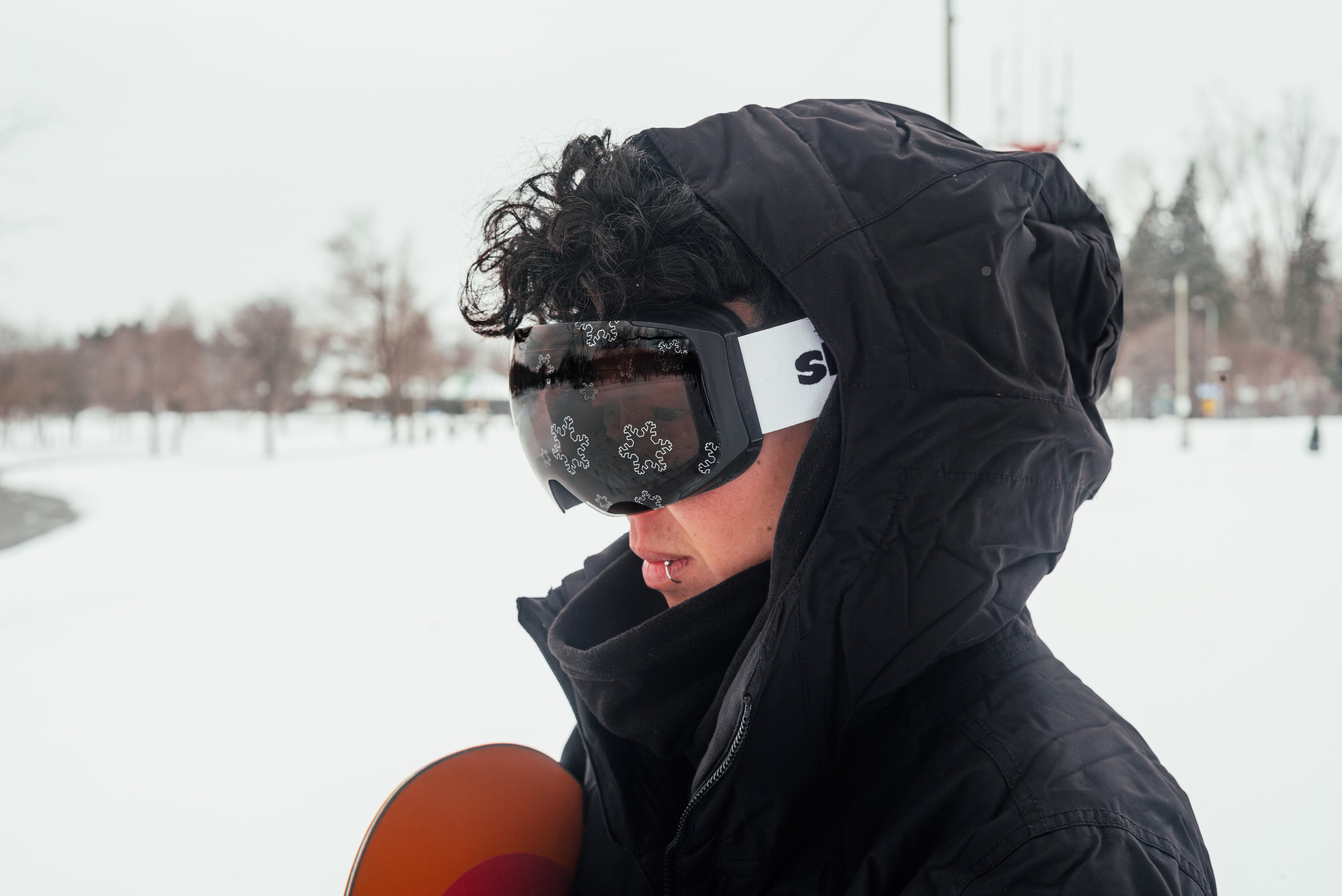 Person wearing white Skoggl ski goggles with interchangeable magnetic snowflake design pattern lens on snowy mountain