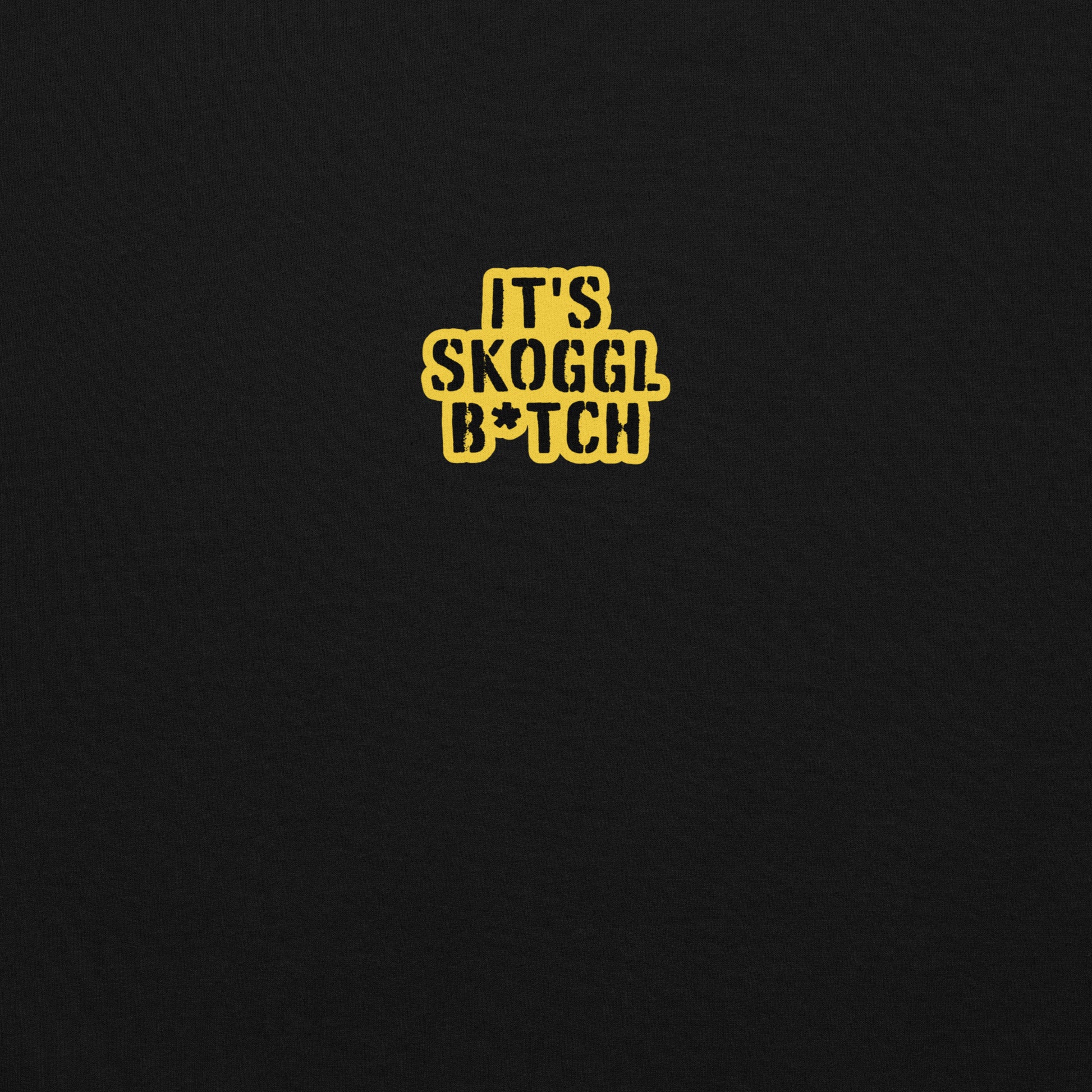 Close-up of the yellow ‘It’s Skoggl B*tch’ patch on a black hoodie.