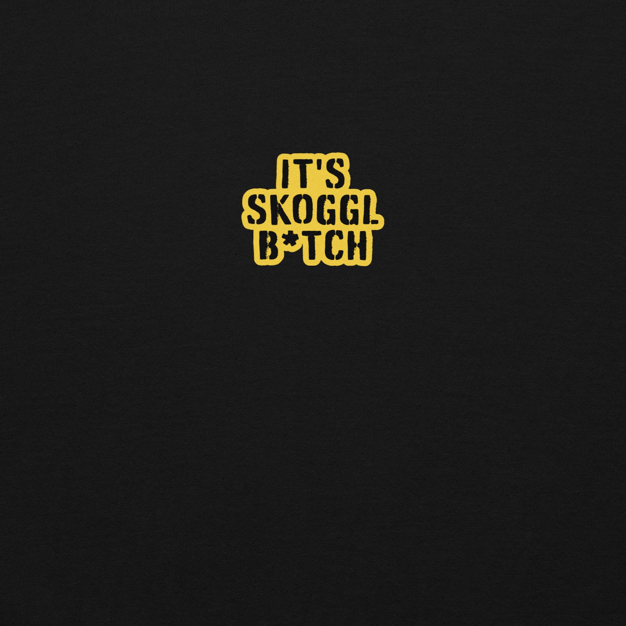 Close-up of the yellow ‘It’s Skoggl B*tch’ patch on a black hoodie.